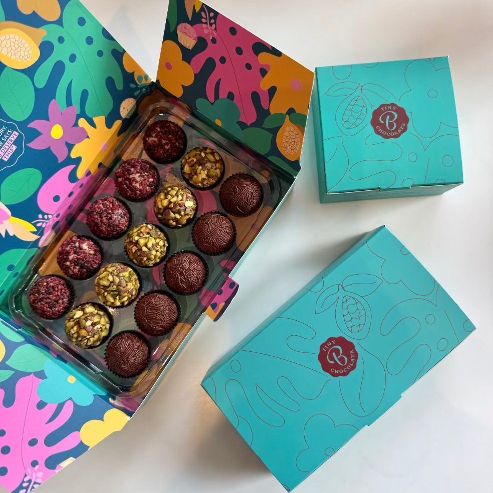 Assorted chocolates in a colorful box with a turquoise branded box on a white background